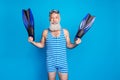 Portrait of cheerful retired pensioner sailor holding fins smiling wearing striped costume isolated over blue background Royalty Free Stock Photo