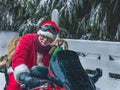 Portrait of a cheerful Santa Claus with a knitted toy on a motorcycle on a snowy street