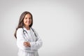 Portrait of cheerful senior european woman doctor in white coat with stethoscope standing with folded arms, copy space Royalty Free Stock Photo