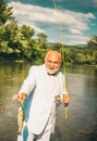 Portrait of cheerful senior man fishing. Grandfather with catch fish. Mature man fisherman in white suit and bowtie with Royalty Free Stock Photo