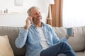 Cheerful mature man talking on cellphone sitting on couch Royalty Free Stock Photo