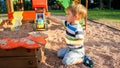 Portrait of cheerful smiling little boy pouring sand in toy truck with trailer. Kids playing and having on playground at Royalty Free Stock Photo
