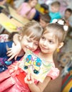 Portrait of cheerful smiling girl holding a bright colorful picture of butterfly painted colors and crayons in kindergarten -