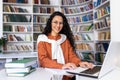 Portrait of cheerful smiling girl student, woman looking at camera sitting studying with laptop, Hispanic woman wearing