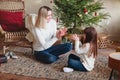 Cheerful smiling little daughter sitting on the floor in living room with her young mother, playing clapping patty-cake game Royalty Free Stock Photo