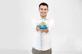 Portrait of cheerful smiling man showing little earth globe to camera, standing isolated over white background. Young Royalty Free Stock Photo