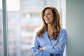 Portrait of cheerful smiling woman standing with arms crossed at glass wall Royalty Free Stock Photo