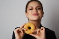 Portrait of a cheerful smiling young caucasian woman holding one donut close her face over white background. Royalty Free Stock Photo