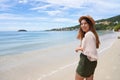 Portrait of cheerful stylish traveler woman on Jurere beach, Florianopolis, Santa Catarina Island, Brazil. Copy space