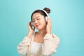 Portrait of a cheerful stylish young woman standing isolated over blue background, listening to music with headphones, dancing Royalty Free Stock Photo