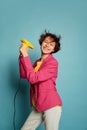 Portrait of cheerful teen girl with curly brown short hair posing with hairdryer isolated over blue background. Getting Royalty Free Stock Photo