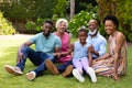 Portrait of cheerful three generational african american family sitting together on grass at garden Royalty Free Stock Photo
