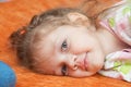 Portrait of cheerful three-year girl lying on the couch