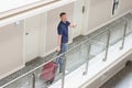 Cheerful tourist man with suitcase search for his room in hotel show thumbs up gesture