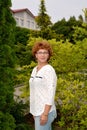 Portrait of the cheerful woman of average years against the background of trees