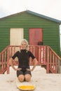 Portrait of cheerful woman kneeling on surfboard against hut Royalty Free Stock Photo