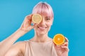 Portrait of cheerful woman with pink hair holding half of fresh orange and covering her eye with lemon half, posing Royalty Free Stock Photo