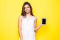 Portrait of a cheerful woman showing blank smartphone screen over yellow background. Royalty Free Stock Photo