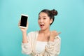Portrait of a cheerful woman showing blank smartphone screen and thumb up over blue background Royalty Free Stock Photo