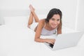 Portrait of a cheerful woman using her laptop lying in bed Royalty Free Stock Photo