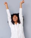 Cheerful young african american woman laughing with arms raised against gray background Royalty Free Stock Photo