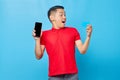 Portrait of cheerful young asian man showing blank screen mobile phone and credit card isolated on blue background