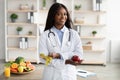 Portrait of cheerful young black female dietician with apple and tape recommending fruits and vegetables, free space Royalty Free Stock Photo