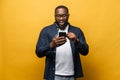 Portrait of cheerful young black guy sending message on mobile phone Royalty Free Stock Photo