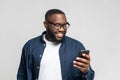 Portrait of cheerful young black guy sending message on mobile phone over white Royalty Free Stock Photo