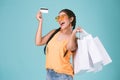 Portrait of cheerful young brunette woman holding credit card and shopping bags Royalty Free Stock Photo