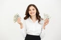 Portrait of a cheerful young business woman holding money banknotes and celebrating over white background. Royalty Free Stock Photo