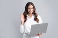 Portrait of a cheerful young casual girl standing isolated over gray background, using laptop computer. Business woman Royalty Free Stock Photo