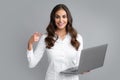 Portrait of a cheerful young casual girl standing isolated over gray background, using laptop computer. Business woman Royalty Free Stock Photo