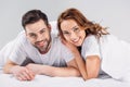 portrait of cheerful young couple in love looking at camera wile lying on bed together Royalty Free Stock Photo