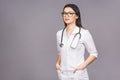 Portrait of cheerful young female doctor with stethoscope over neck looking at camera isolated on grey background Royalty Free Stock Photo