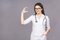 Portrait of cheerful young female doctor with stethoscope over neck looking at camera isolated on grey background. Presenting your Royalty Free Stock Photo