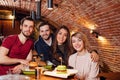 Portrait of cheerful young friends enjoying night out at modern pub. Royalty Free Stock Photo