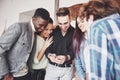 Portrait of cheerful young friends looking at smart phone while sitting in cafe. Mixed race people in restaurant using Royalty Free Stock Photo