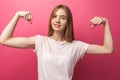 Portrait of cheerful young girl bending biceps on pink background, cute and attractive, Royalty Free Stock Photo