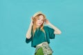 Portrait of a cheerful young girl in a summer hat, dressed in summer clothes posing on blue background Royalty Free Stock Photo