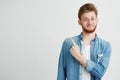 Portrait of cheerful young handsome guy smiling looking at camera pointing finger up over white background. Royalty Free Stock Photo