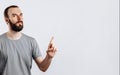 Portrait of cheerful young handsome man smiling looking at camera pointing finger upwards on white background with space for Royalty Free Stock Photo