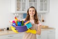 Portrait of cheerful young housewife holding cleaning supplies, smiling and looking at camera in kitchen Royalty Free Stock Photo