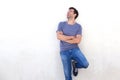 Cheerful young man with arms crossed laughing against white wall Royalty Free Stock Photo