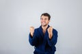 Portrait of cheerful young man, positive smiling  raising fists in victory or win gesture wearing blue bathrobe, isolated over Royalty Free Stock Photo