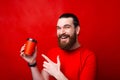 Portrait of cheerful young man smiling and pointing at coffee cup to go over red background Royalty Free Stock Photo