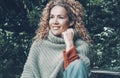 Portrait of cheerful young mature woman smiling and enjoying outdoor leisure activity sitting at the park with green trees and