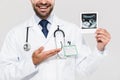 Portrait of cheerful young medical doctor working in hospital and holding ultrasound scan of baby Royalty Free Stock Photo