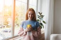 Young smiling red hair woman in comfy knitted warm sweater holding yellow coffee cup Royalty Free Stock Photo