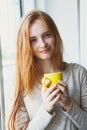 Portrait of cheerful young smiling red hair woman holding yellow coffee cup, enjoying morning coffee and new day, waking up Royalty Free Stock Photo